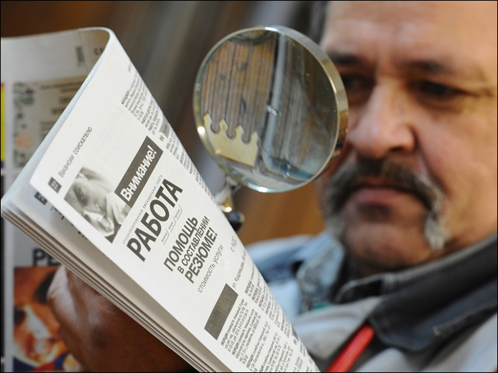 Мужчина читает газету с вакансиями